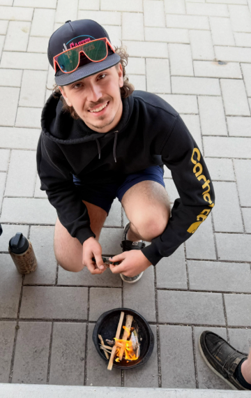 Man kneeling, practicing individual fire starting using flint